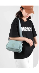 Detailed view of light blue nylon crossbody bag with multiple zipper pockets and strap