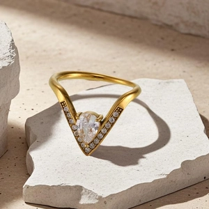 Détail d'une bague en V dorée avec pierre en poire et pavage micro-serti sur support pierre