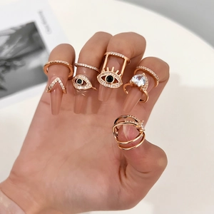 Detail of six rose gold rings with cubic zirconia evil eye and heart motifs on a hand