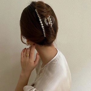 Detail of elegant pearl claw clip in Korean style on brown hair for women