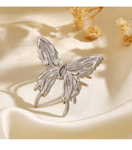 Detailed close-up of a silver butterfly ring on elegant cream silk with dried flowers