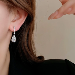 Close-up of silver waterdrop tassel earrings with shimmering crystals on a model