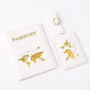 Close-up of white PU leather passport holder and luggage tag with gold world map pattern