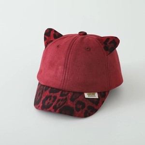 Détail d'une casquette rouge pour enfant avec oreilles léopard et texture en daim