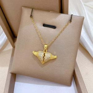 Macro detail of gold broken heart pendant with clear crystals on beige velvet jewelry box