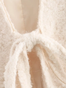 Detailed close-up of beige fuzzy knit cardigan featuring a delicate front tie-up closure