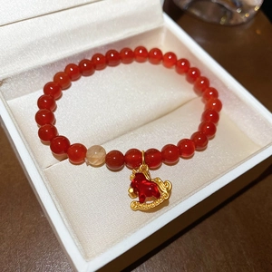 Détail du bracelet en perles d'agate rouge avec pendentif cheval à bascule doré