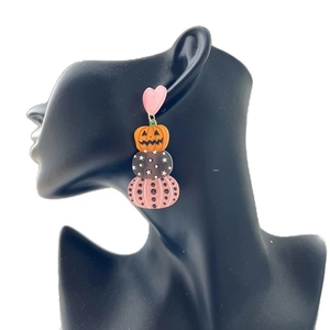 Halloween acrylic dangle earrings with pink hearts and pumpkin motifs on a model display