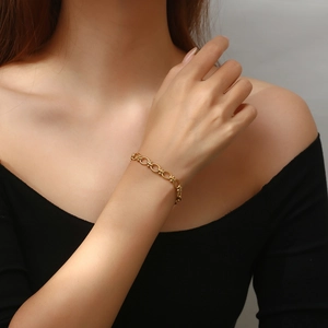 Detail of gold-plated stainless steel U-link bracelet worn on a woman's wrist