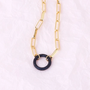 Close-up of gold paperclip chain necklace with dark blue gemstone circle pendant