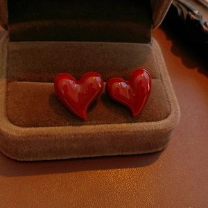 Macro shot of red heart stud earrings with glossy finish in a brown velvet jewelry box