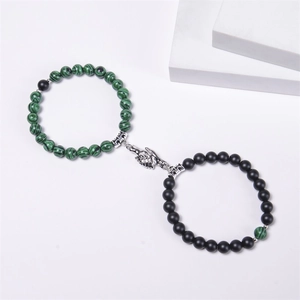 Detail of magnetic handshake charms connecting green malachite and black matte beaded bracelets