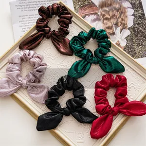 Detailed view of five metallic pleated scrunchies with ribbons in various festive colors