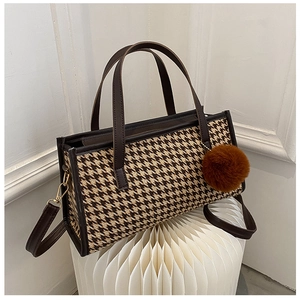 Detail of houndstooth pattern fabric and leather strap on a brown crossbody bag