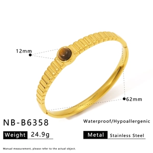 Detail of gold-plated stainless steel cuff featuring a brown tiger eye stone inlay