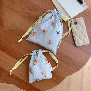Blue striped cotton drawstring bags with cute bear prints and side brand label on wood