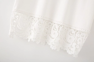 Détail de l'ourlet en dentelle blanche et de la texture fluide du tissu de ce t-shirt