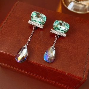 Dettaglio di orecchini in argento con zircone verde e cristallo iridato su scatola in pelle