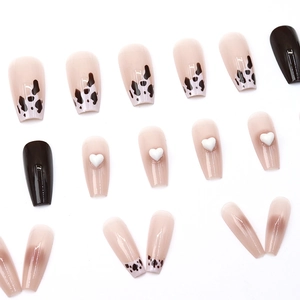 Long coffin press-on nails with cow print, heart charms, and black glossy finish