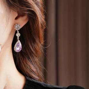Close-up of model wearing silver vintage drop earrings with purple teardrop crystals