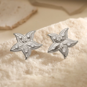 Star-shaped silver stud earring with sparkling zircons on a marble stone background
