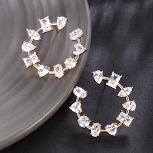Detailed macro view of C-shaped gold earrings with mixed-cut cubic zirconia stones
