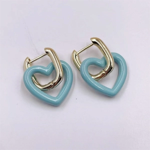 Détail des boucles d'oreilles cœur bleu ciel avec un design géométrique doré de luxe