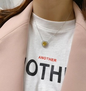 Close-up of heart-shaped yellow gemstone pendant necklace with halo diamond set on a model