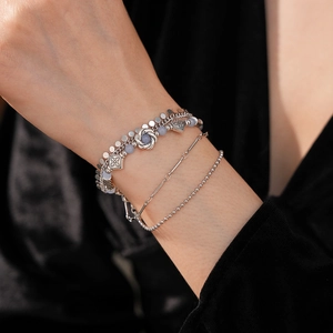Detail of bohemian multilayer bracelet with silver charms and blue beads on model wrist