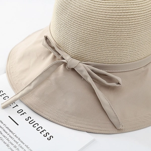 Detail view of woven straw sun hat with ribbon bow and contrast fabric stitching
