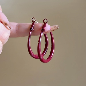 Close-up of elegant burgundy oval hoop earrings with a glossy metal finish