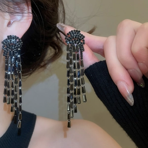 Gros plan de boucles d'oreilles à pampilles noires avec cristaux portées par un mannequin