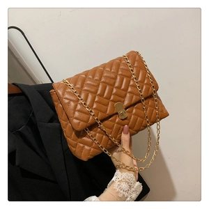 Detail of brown quilted chain bag with gold rotary lock and V-stitch pattern texture