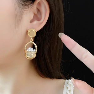 Close-up of vintage gold hollow basket earrings with white pearls on a model