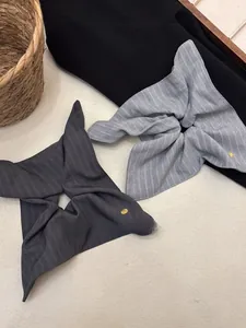 Close-up of grey and blue striped fabric hair scrunchies with small gold metal emblems