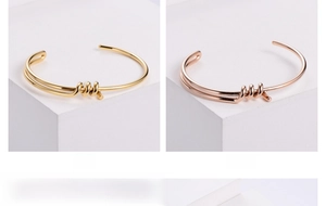 Detail of knotted gold and rose gold titanium steel bangles on minimalist pedestals