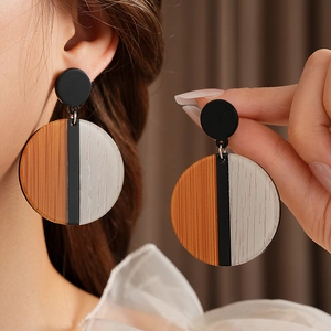 Gros plan de boucles d'oreilles rondes en bois et résine avec textures et clous en argent