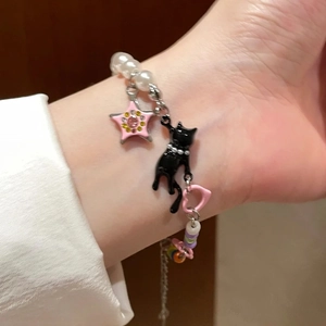 Y2K pearl bracelet with black cat and pink star charms on model wrist