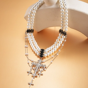 Detail of double-layer faux pearl necklace with rhinestone cross pendant on display