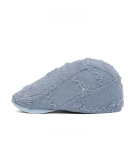 Close-up of light blue denim ivy cap featuring floral lace embroidery and wavy stitching