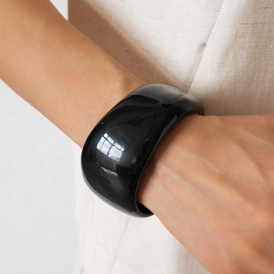 Close-up of wide black acrylic bangle with mirror polish on a model's wrist