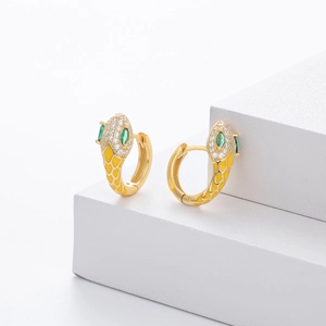 Detail of gold snake earrings with yellow enamel, green gem eyes and clear zircons