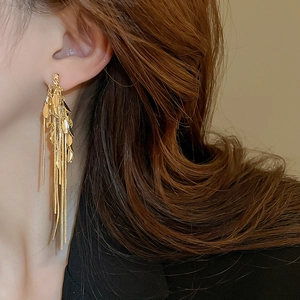 Close-up of golden long tassel wheat ear earrings worn by a model for a stylish look