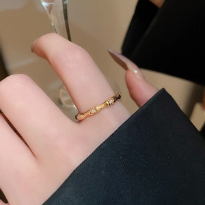 Close-up of gold bamboo-shaped open ring with zircon accents on a person hand