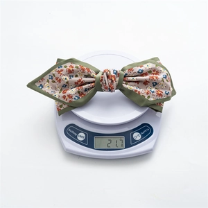 Floral satin bow hair clip on a digital scale weighing 21.7g for weight display