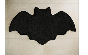 Detailed top view of black bat-shaped Halloween floor mat on light beige tile floor