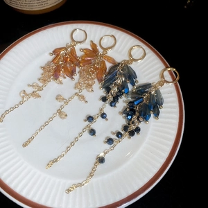 Bohemian crystal teardrop tassel earrings in amber and blue on a decorative porcelain plate