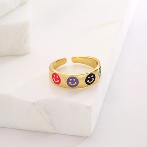 Detail of gold-plated open ring featuring colorful enamel smiley face patterns