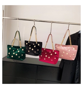 Detail view of velvet tote bags in four colors with decorative golden sunflower metal studs