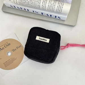 Detail of black corduroy mini pouch with pink zipper pull and woven brand label